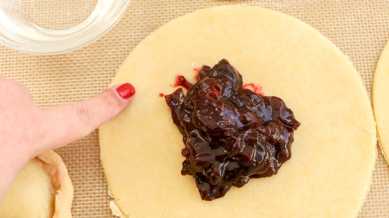 Les bords de pâte empanada humidimentés avec de l'eau