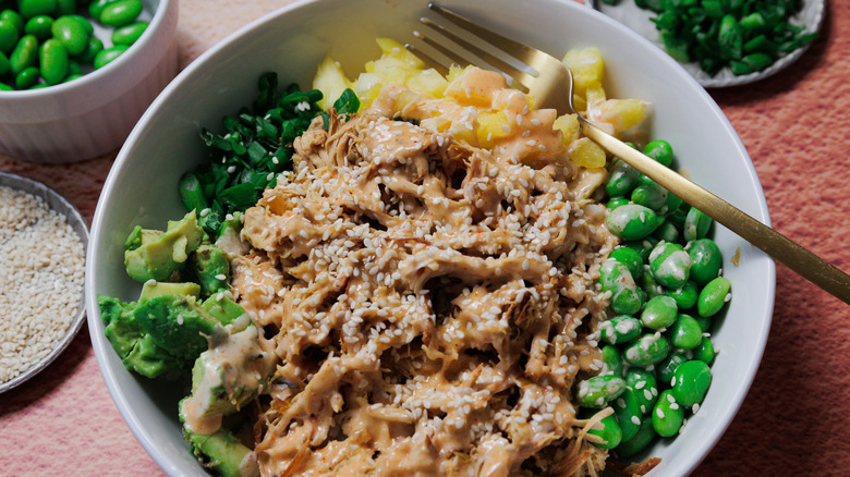 Bol de poulet hawaïen avec edamame, graines de sésame, oignons verts en arrière-plan
