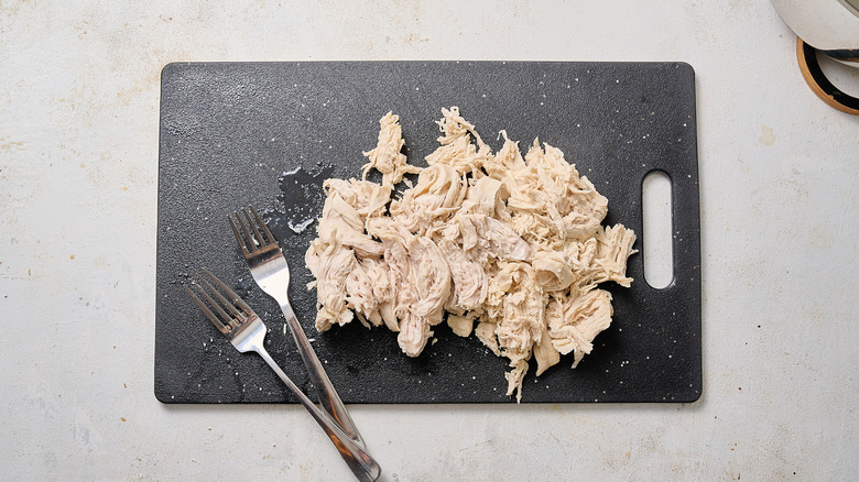déchiqueter le poulet sur la planche à découper