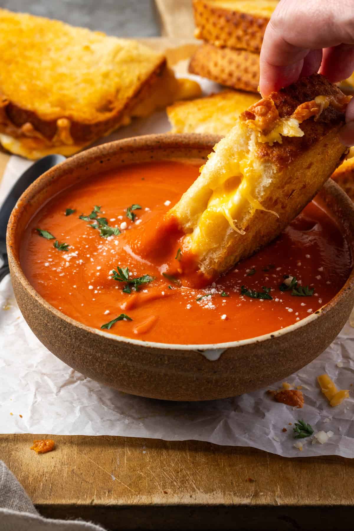 Ce fromage grillé aux frites à air prend des minutes à faire et sort doré à l'extérieur, parfaitement gluant à l'intérieur, avec de grandes cordes de fromage fondant! Une main trempe d'une tranche de fromage grillé à la friteuse dans un bol de soupe aux tomates.