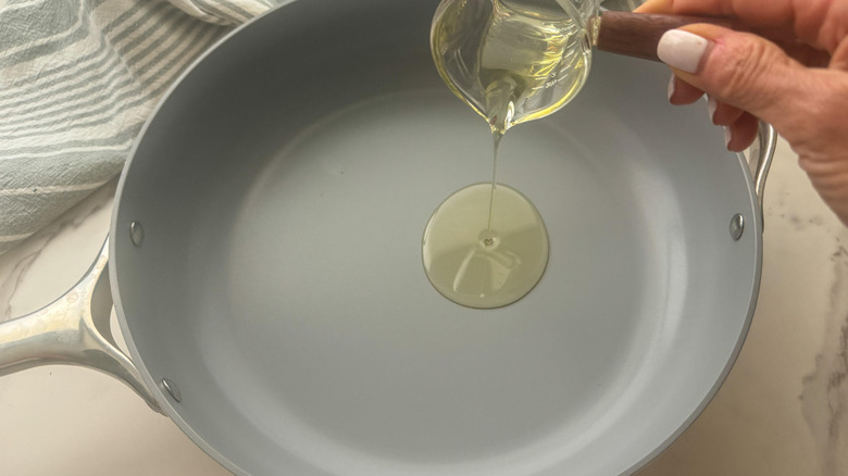 Ajout d'huile d'ajout à la main à la casserole grise