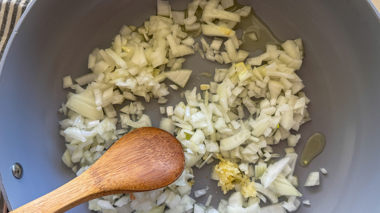 Oignon et ail dans la casserole avec cuillère en bois