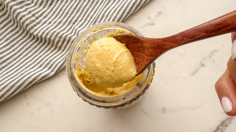 Crème de noix de cajou de la capture à la main avec un mélangeur avec une cuillère en bois