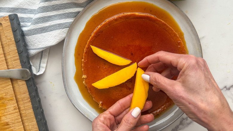 Ajout de tranches de mangue à la mangue sur le flan sur une assiette blanche