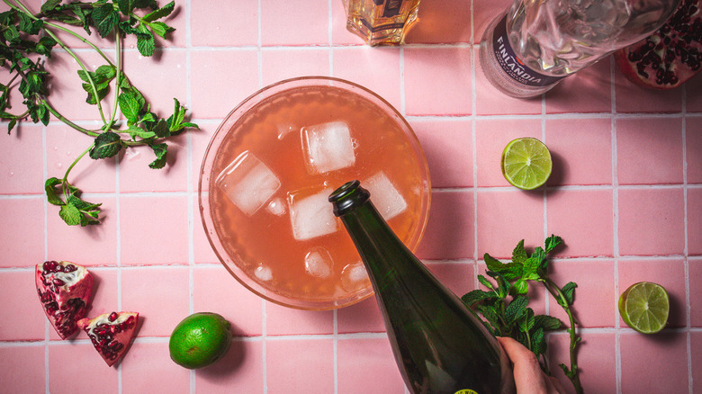 Ajouter du vin rose dans un grand bol avec du punch rose et des garnitures tout autour