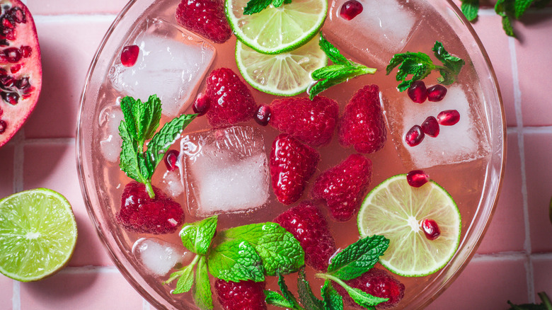 Un bol de punch rose avec des garnitures vertes