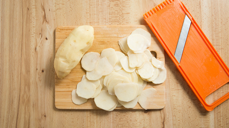Pommes de terre en tranches sur la planche à découper
