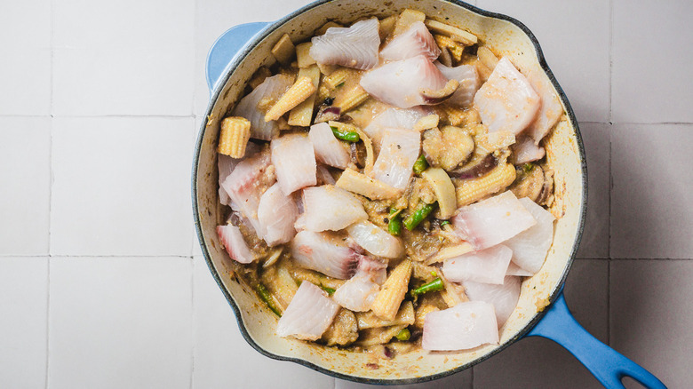 Pièces de poisson ajoutées à la casserole avec du curry