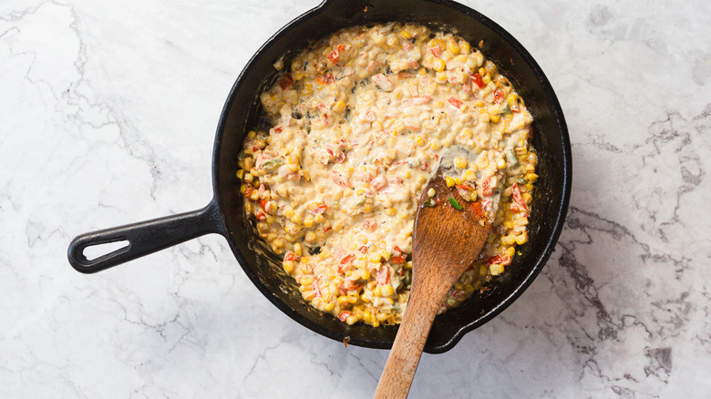 Casserole de maïs de rue crémeuse avec spatule en bois