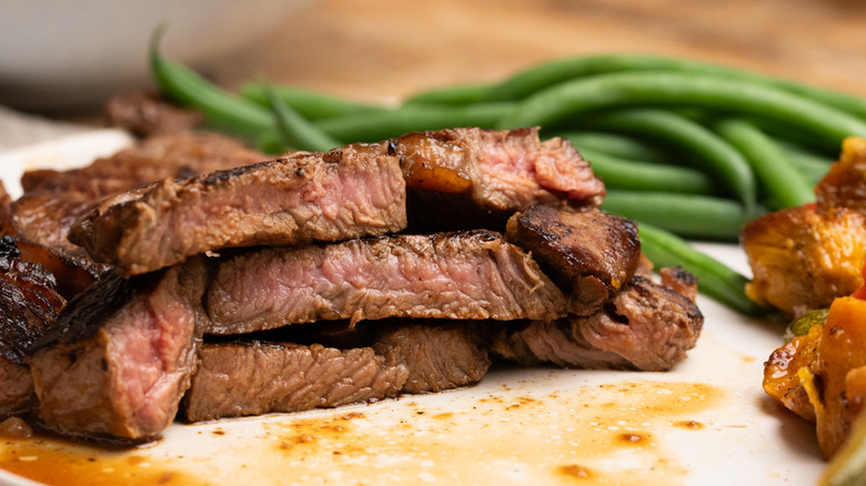 Des piles de steak coarmé coupé sur la plaque à côté des haricots verts