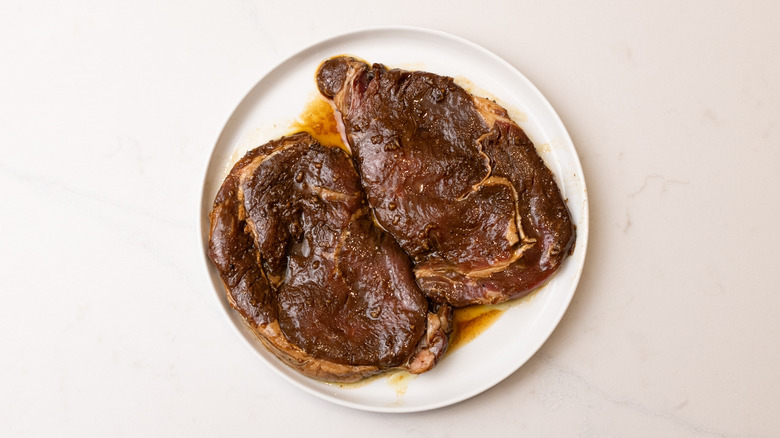 Deux morceaux de steak mariné sur une assiette blanche