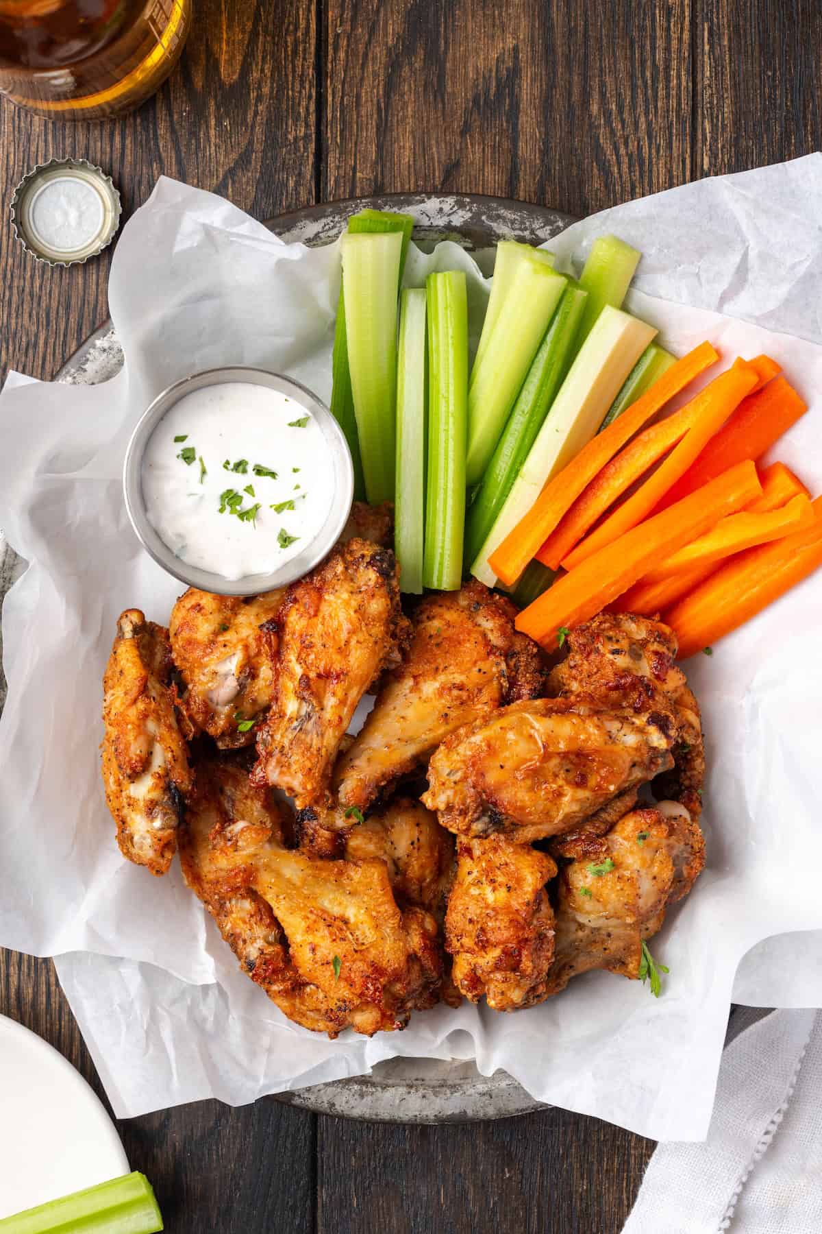 Faites les ailes de poulet à air de style pub les plus croustillantes! Cette méthode est rapide, sans gâchis et facile à personnaliser. Ajoutez votre sauce aile préférée! Vue aérienne des ailes de poulet à la friteuse à air dans un panier de service avec crudités et un côté de la vinaigrette en ranch.