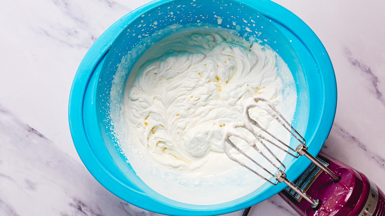 Crème fouettée dans un bol avec un mélangeur à main