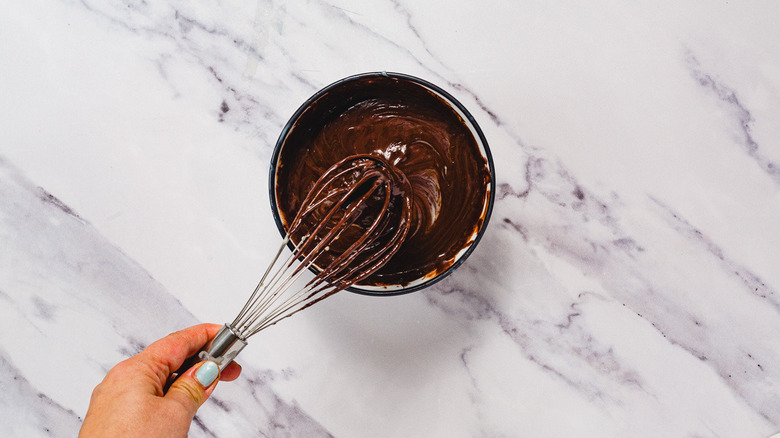 Fouetter du chocolat fondu et du lait condensé dans un bol