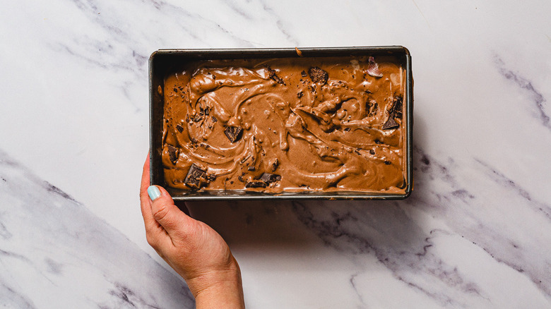 Hand tenant une glace au chocolat dans un récipient