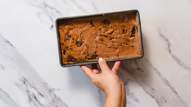 Main tenant la glace au chocolat congelée dans un récipient