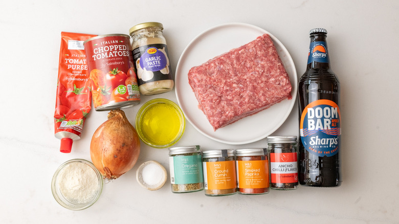 Assiette de Chuck de boeuf haché, une boîte de tomates hachées, un pot de pâte d'ail et d'autres ingrédients du piment de l'ouest du Texas.