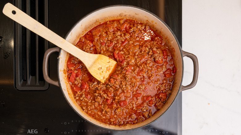 West Texas Chili mijoté sur la cuisinière avec une spatule en bois à l'intérieur