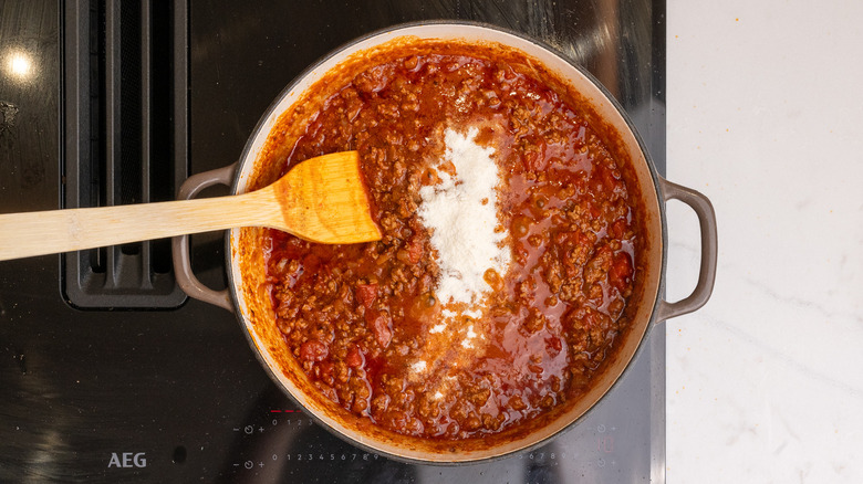 Masa Harina a ajouté à une casserole de chili sur la cuisinière avec spatule à l'intérieur