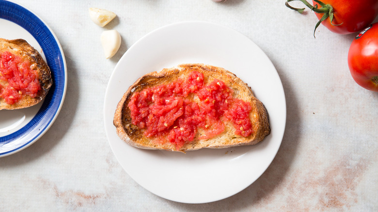 Pan Con Tomate sur les assiettes à côté des gousses d'ail