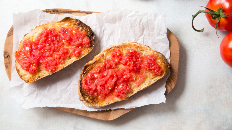 Two Pan Con Tomate sur une planche en bois doublée avec des tomates sur le côté