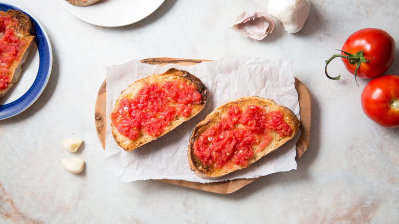 Pan Con Tomate à bord entouré de tomates et d'ail