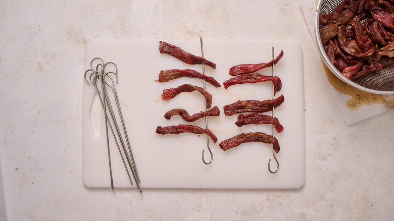 mettre des tranches de viande séchée sur des brochettes