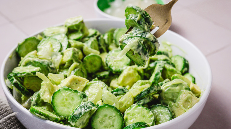 Soulever une fourchette de salade de concombre avocat du bol